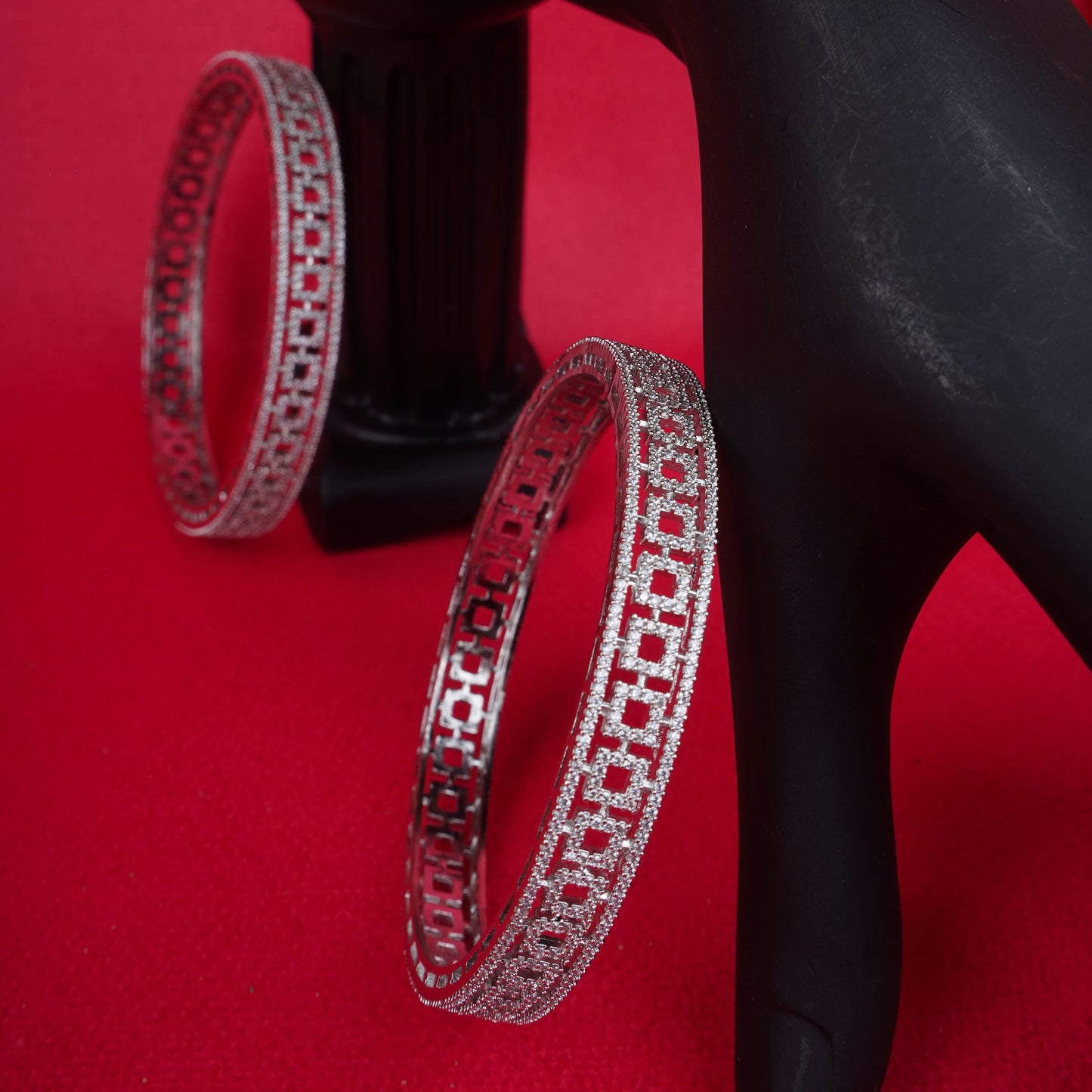Silver geometric cut bangles with crystal detailing on red background - Revaaj Ground