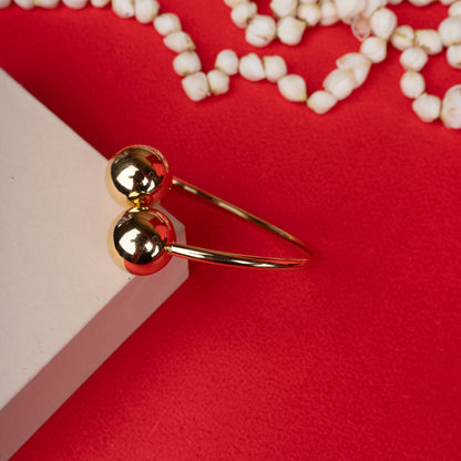 Gold-tone open bangle bracelet with dual polished spheres white backgroung - Revaaj