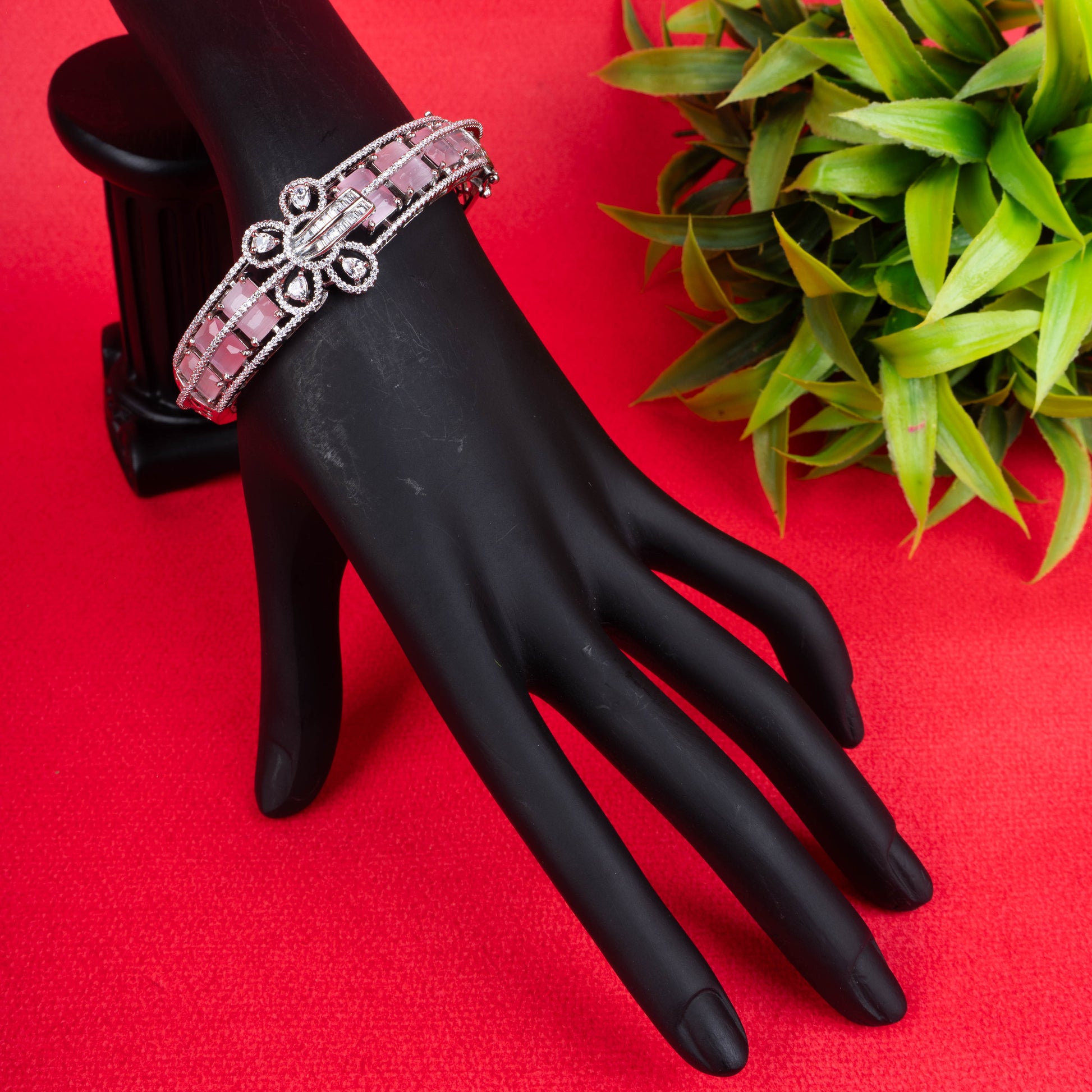 Silver-tone hinged bracelet with a row of pale pink gemstones, a central crystal-encrusted bow, and a crystal-paved band - Revaaj