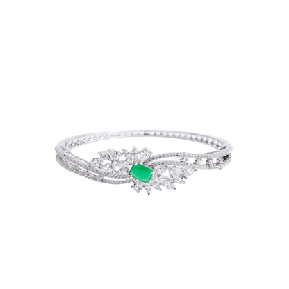 Silver-tone hinged bracelet with a prominent emerald-cut green gemstone at its center, surrounded by clear marquise and round crystals, and a band paved with micro-crystals white image - Revaaj