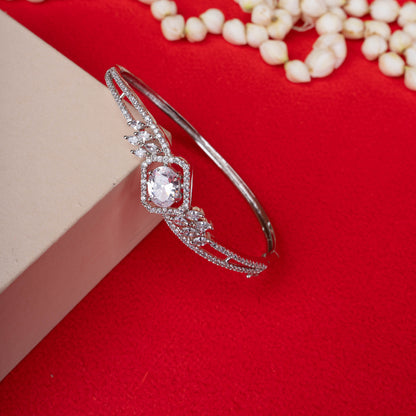 Ornate silver-tone hinged bracelet with a large oval-cut crystal at the center, surrounded by a halo of smaller crystals and winged accents ground image  - Revaaj
