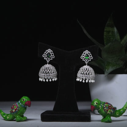 Classic CZ jhumka earrings with green stone accent displayed on black stand 