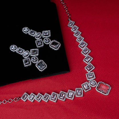 Necklace and earring set with square and round clear stones in halo design on red background