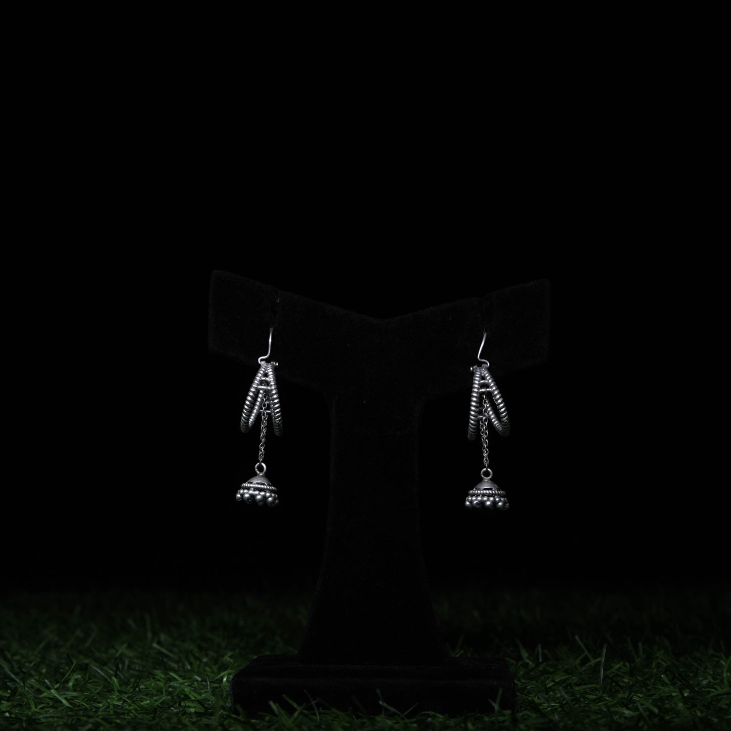 Minimal oxidized silver dangler earrings with dome charms displayed on black stand 