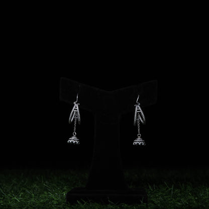 Minimal oxidized silver dangler earrings with dome charms displayed on black stand 