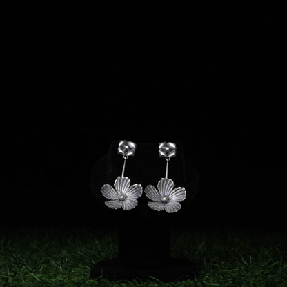 Oxidized silver floral dangler earrings with intricate petal design displayed on black stand