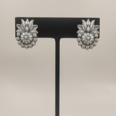 Oxidized silver floral stud earrings with intricate design displayed on a black stand