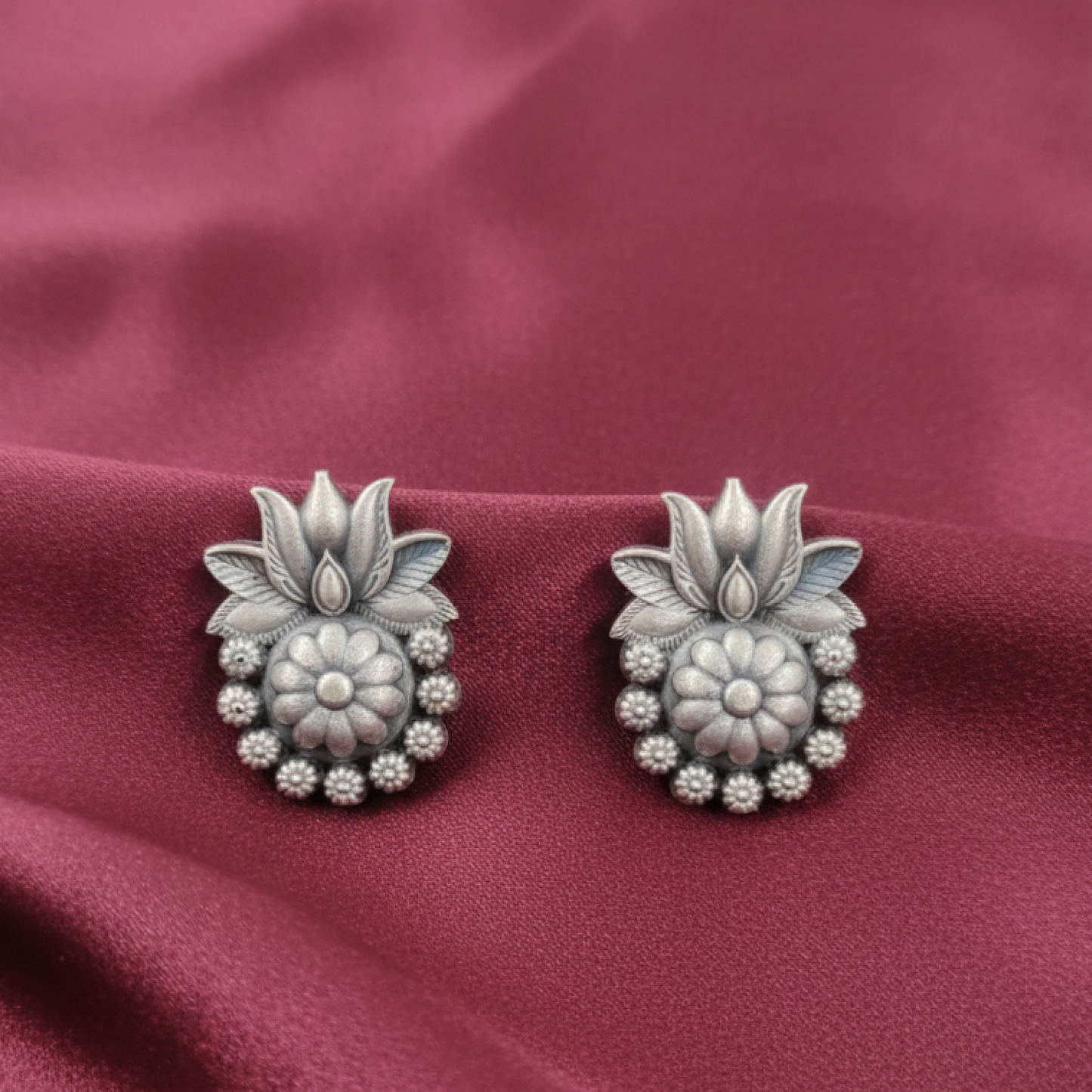 Oxidized silver floral stud earrings with intricate design displayed on a black stand white