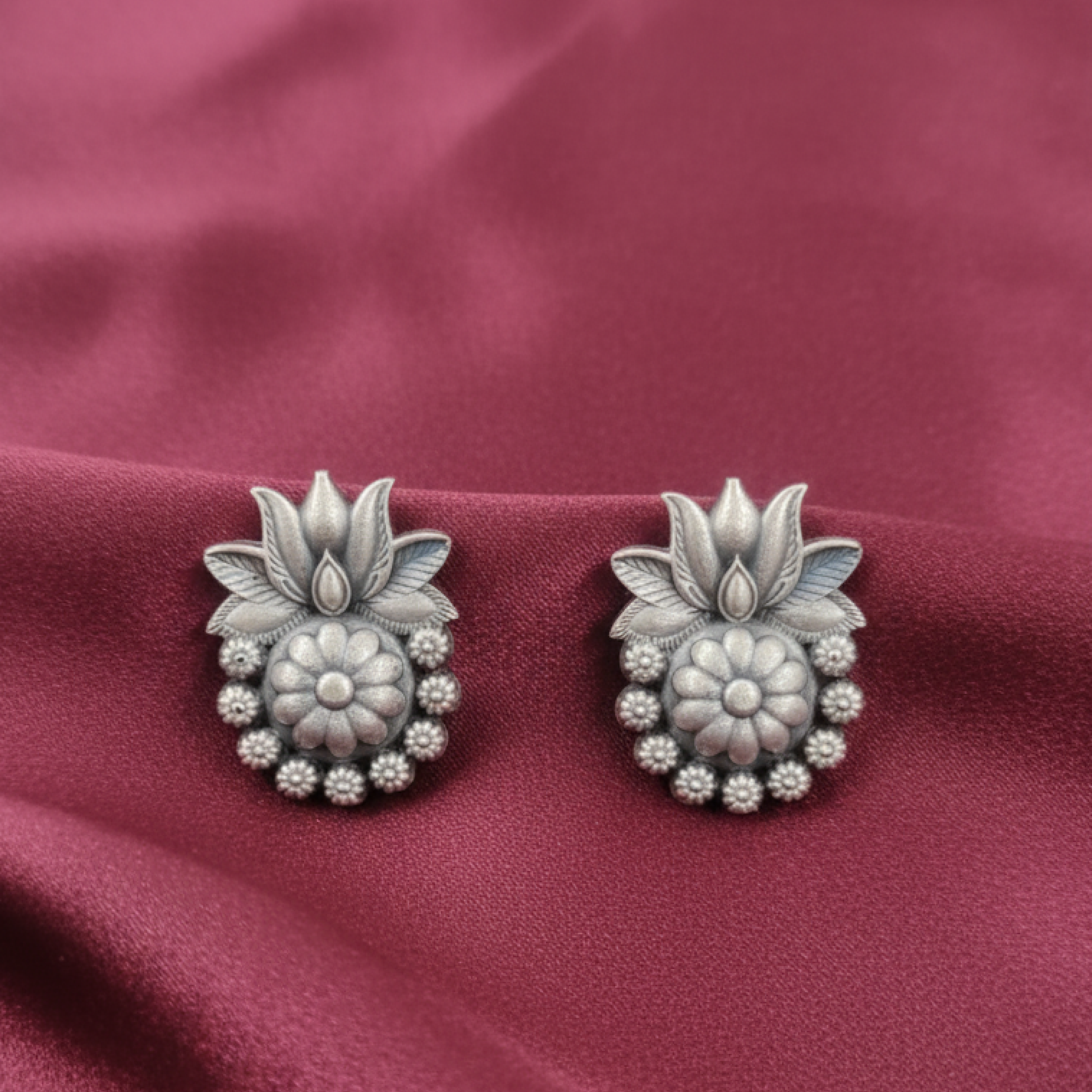 Oxidized silver floral stud earrings with intricate design displayed on a black stand white