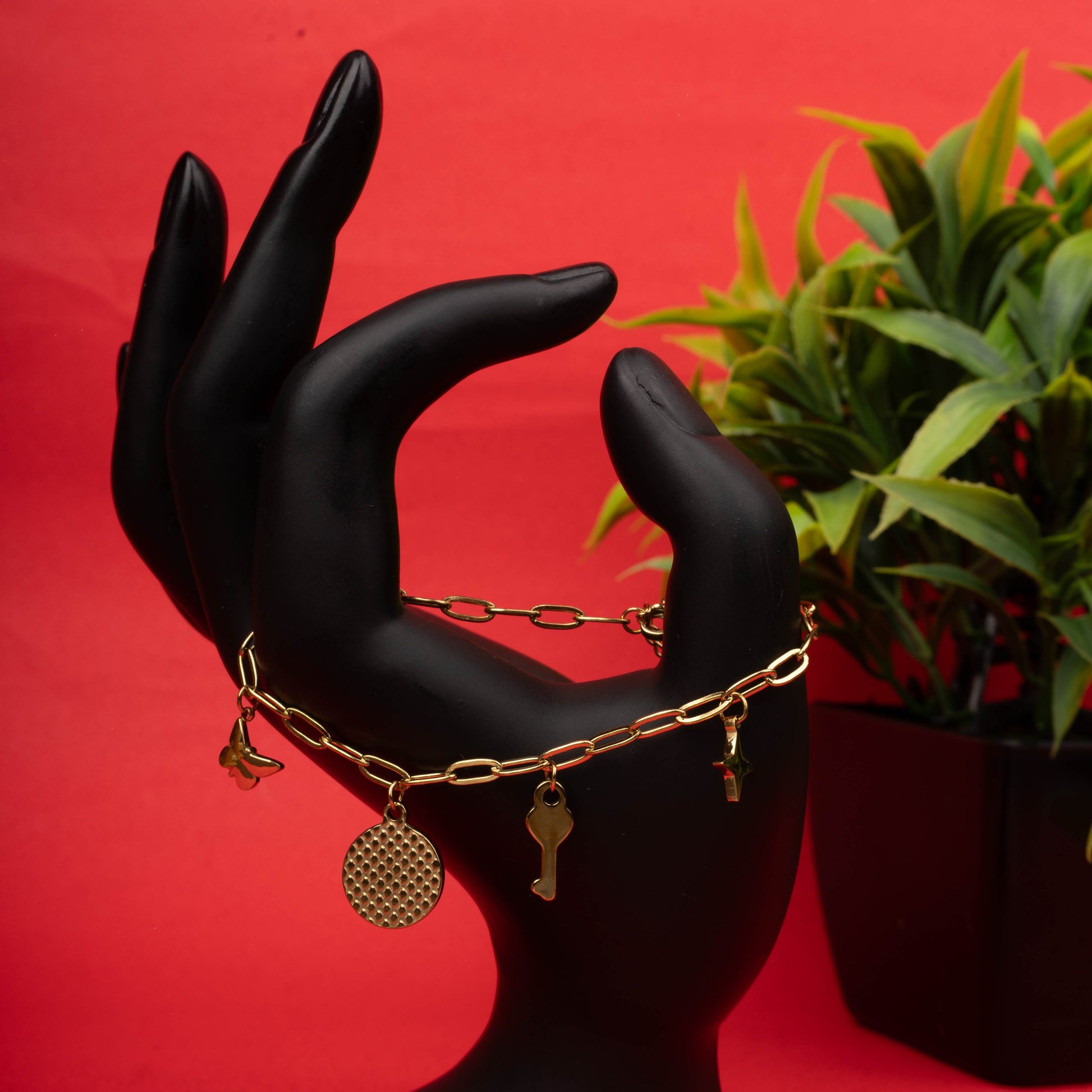 Gold paperclip chain bracelet with butterfly, key, and textured medallion charms - Revaaj