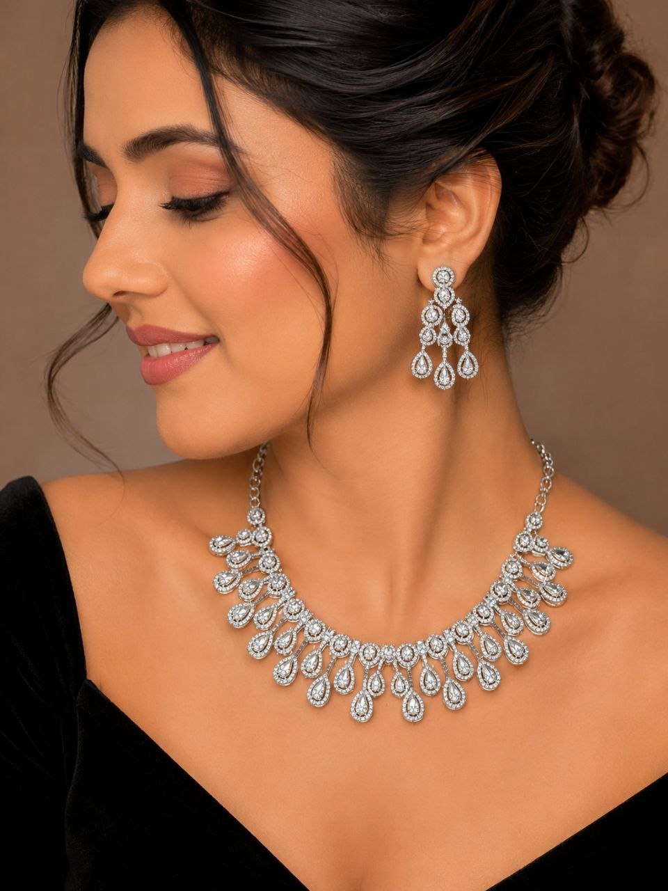 Luxury silver teardrop American diamond necklace and matching earrings set displayed on beige jewelry bust with soft beige background 2
