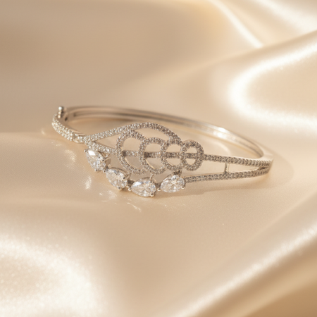 Elegant silver diamond bracelet with teardrop-shaped stones resting on soft beige satin fabric