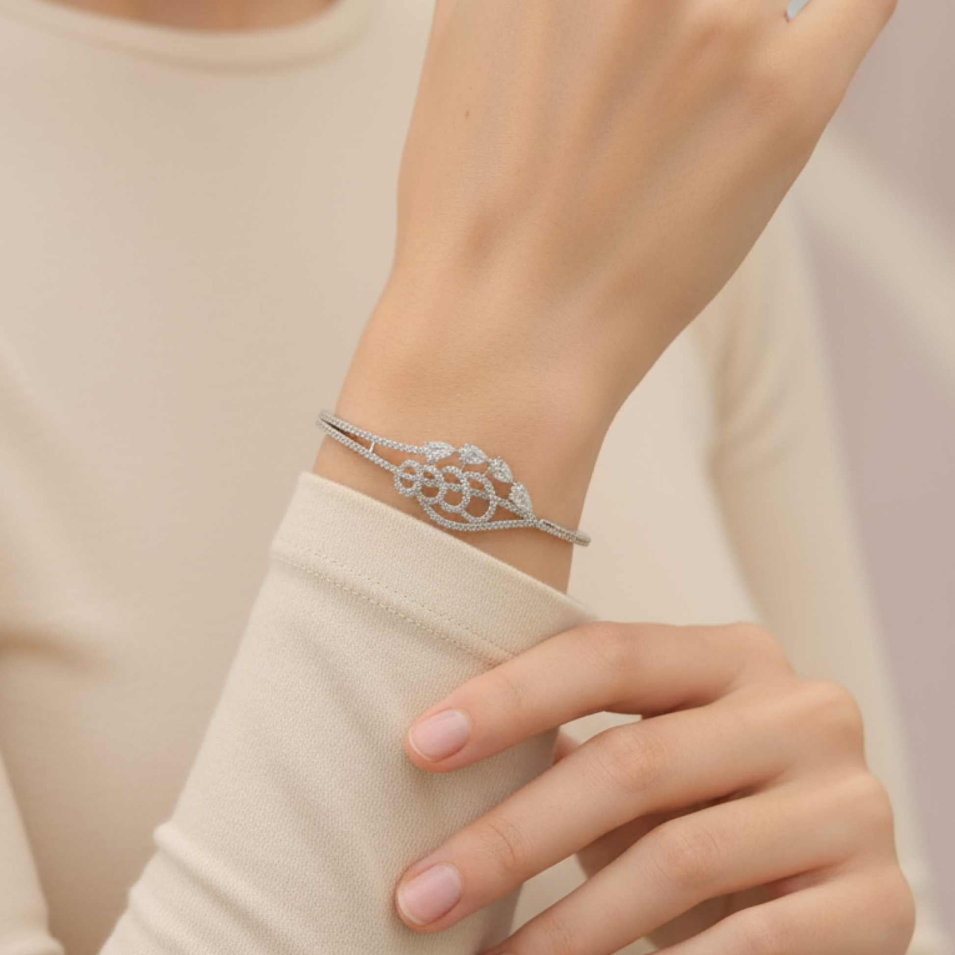 Elegant silver diamond bracelet with teardrop-shaped stones resting on soft beige satin fabric stand