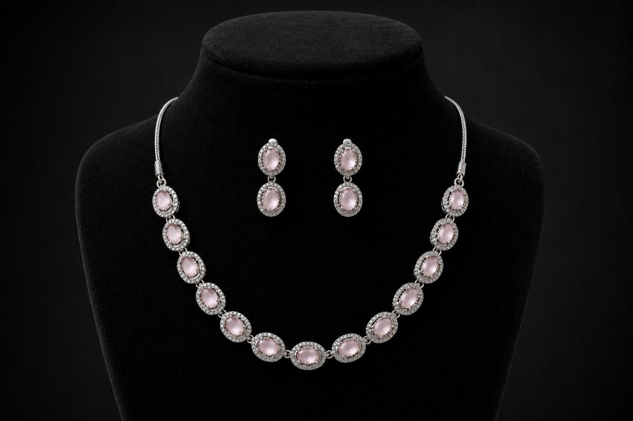 Silver-toned necklace with multiple oval pink gemstones in pave settings paired with matching drop earrings displayed on a beige jewelry bust 2