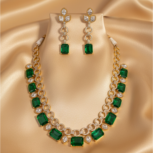 Emerald gold necklace set with matching earrings featuring green stones and diamond accents on satin background