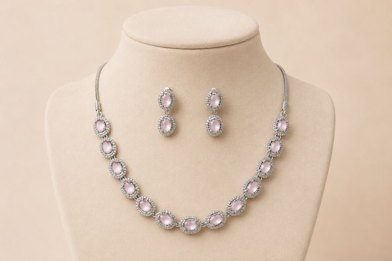 Silver-toned necklace with multiple oval pink gemstones in pave settings paired with matching drop earrings displayed on a beige jewelry bust 1