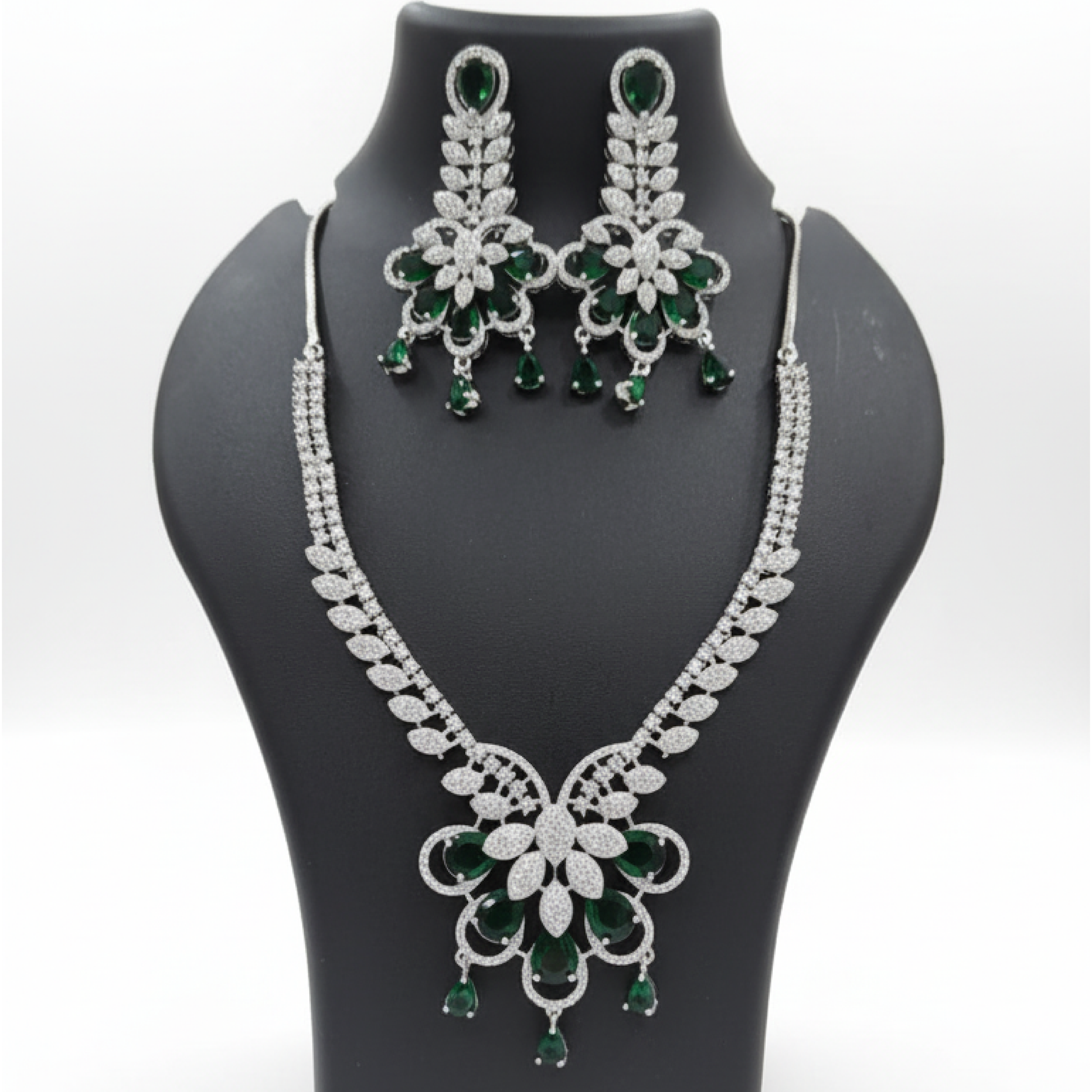 Emerald royal bloom necklace set with matching earrings featuring green pear-shaped stones and diamond detailing on satin background white