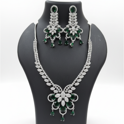 Emerald royal bloom necklace set with matching earrings featuring green pear-shaped stones and diamond detailing on satin background white