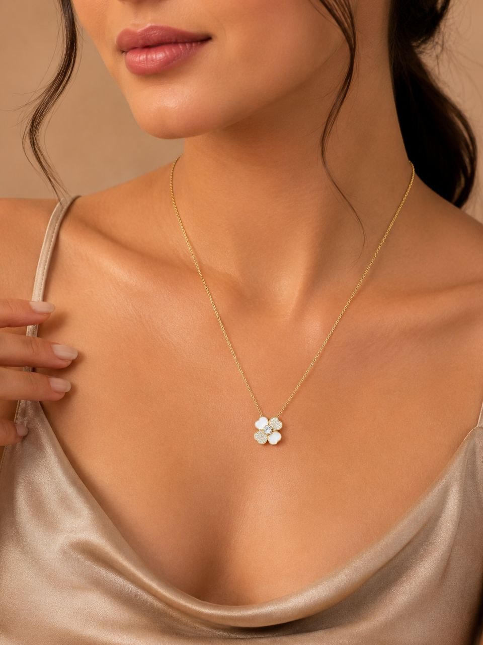 Delicate gold chain necklace with white four-petal floral pendant featuring sparkling crystal stones on beige background 2
