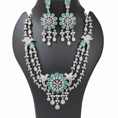 Aqua green double-layered necklace set with matching earrings featuring floral design and diamond detailing on black display white
