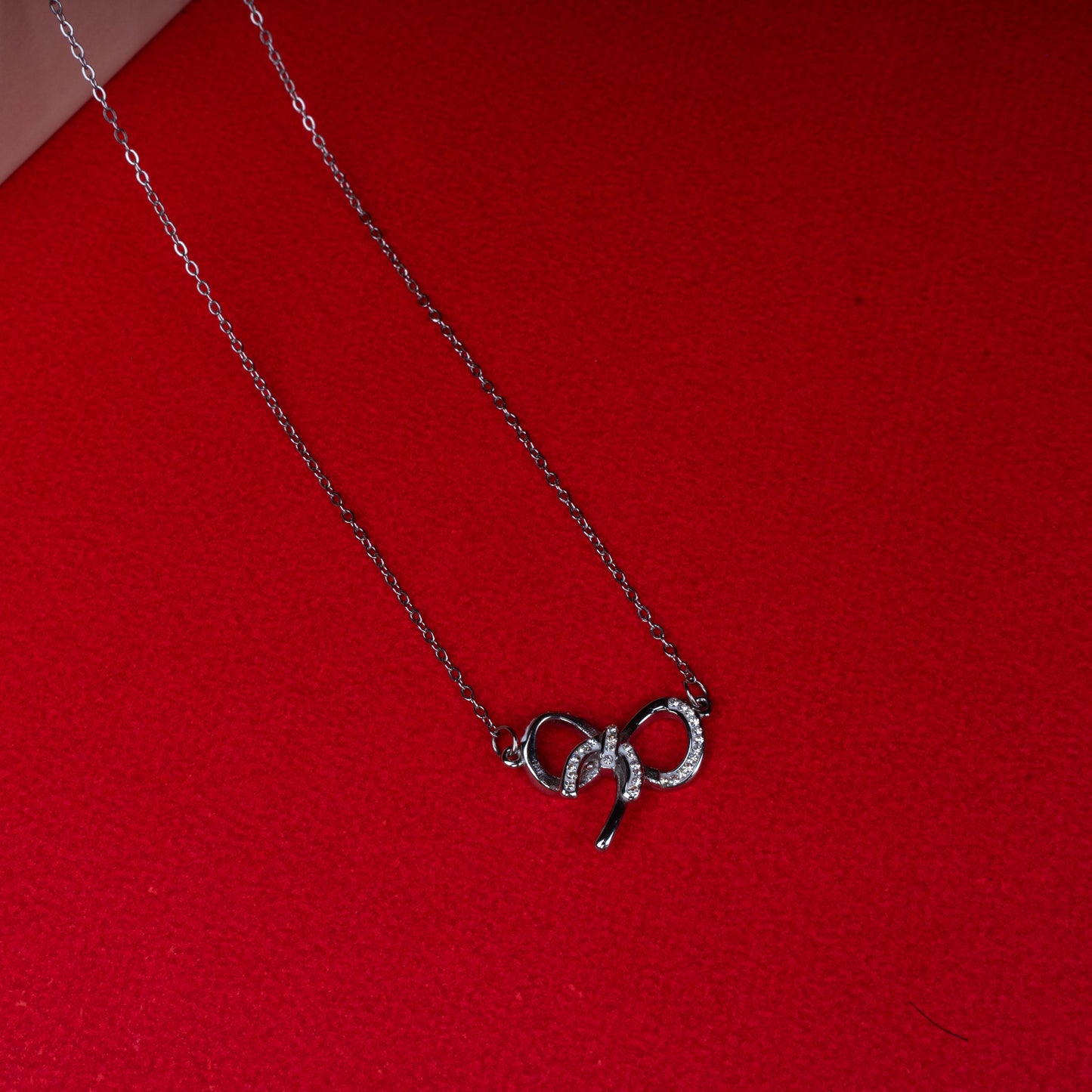 Silver bow pendant necklace with sparkling stone detailing second view - Revaaj