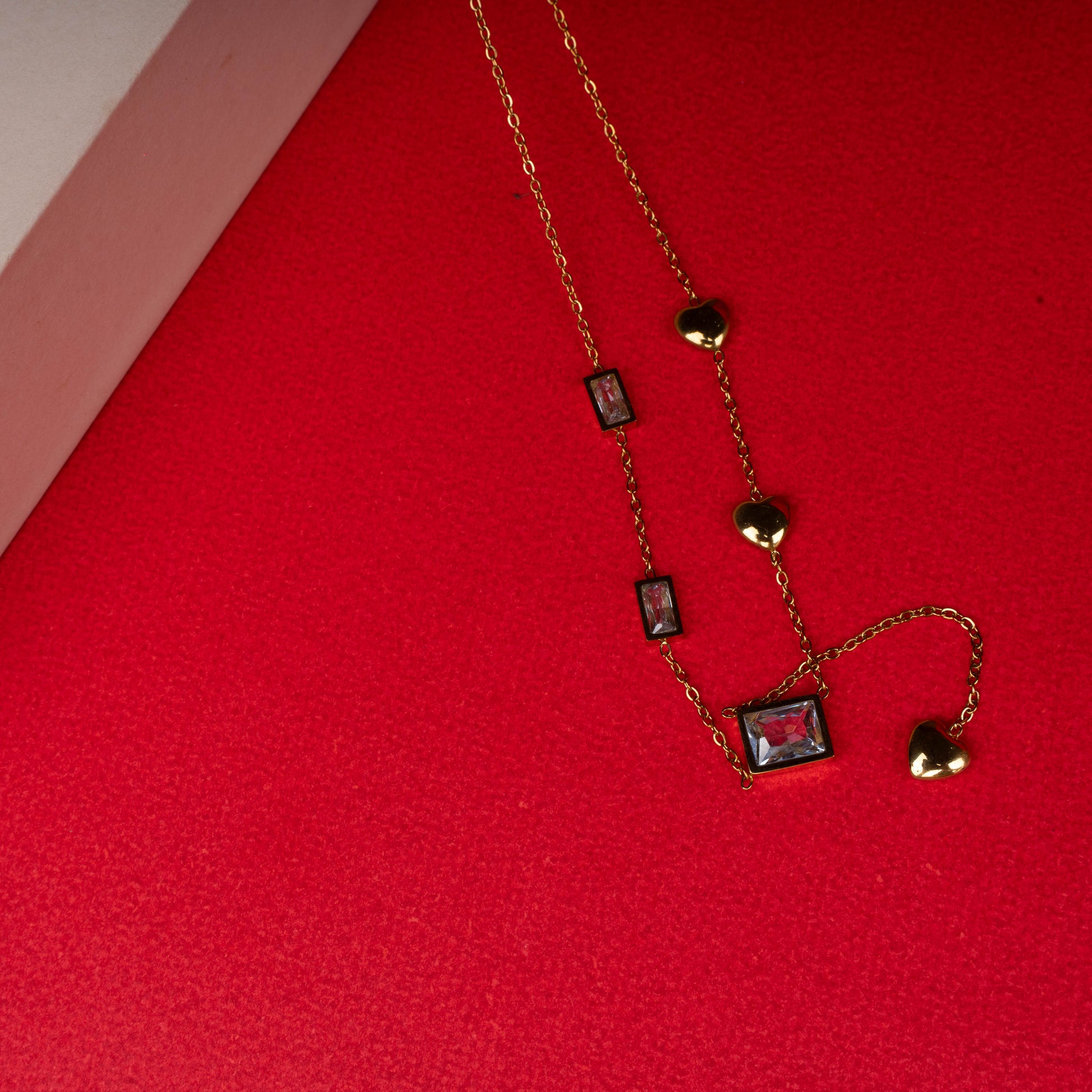 Gold necklace with red rectangular gemstones and heart charms floored image - Revaaj