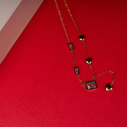 Gold necklace with red rectangular gemstones and heart charms floored image - Revaaj
