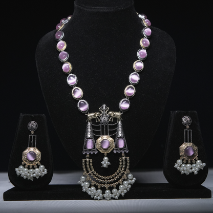 Revaaj Kundan necklace set with lavender gemstones and pearl earrings displayed on a black jewelry stand.