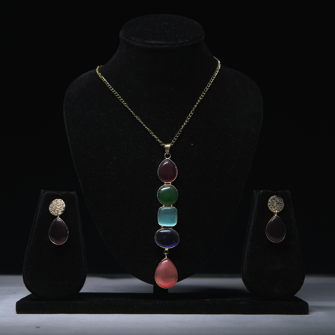 Revaaj multicolored stone necklace and earring set displayed on a black jewelry stand.