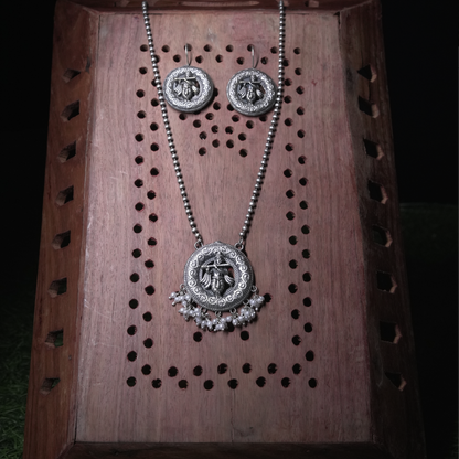Revaaj Oxidized Silver Krishna Pendant Necklace with pearl accents, displayed on a wooden background.