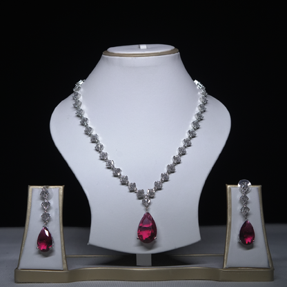 Revaaj Ruby and Cubic Zirconia Necklace and Earring Set displayed on a white stand against a black background.