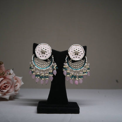 Pastel pink and blue chandbali earrings with pearl drops displayed on a black velvet stand.