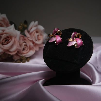 Pink enamel floral stud earrings with gold accents on black velvet display.