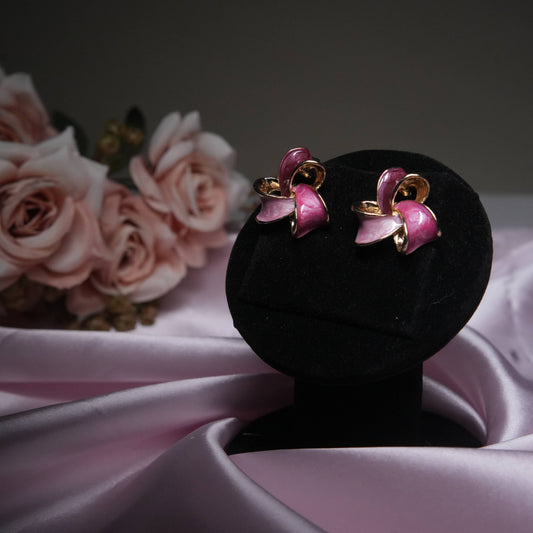 Pink enamel floral stud earrings with gold accents on black velvet display.
