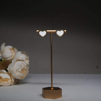 Classic white heart stud earrings with antique beaded detailing displayed on a golden stand.