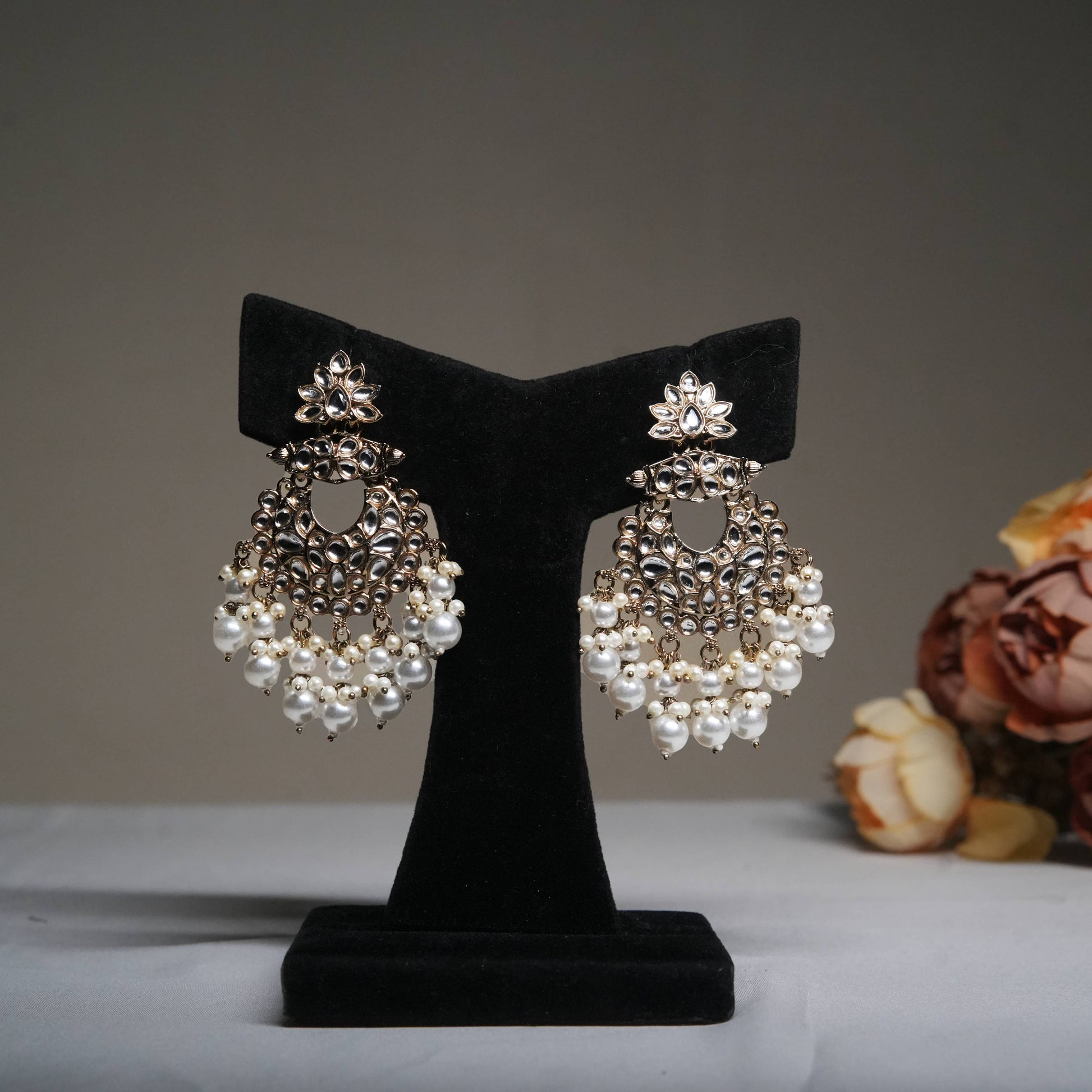 Royal pearl tassel chandbali earrings with kundan accents displayed on a black velvet stand.
